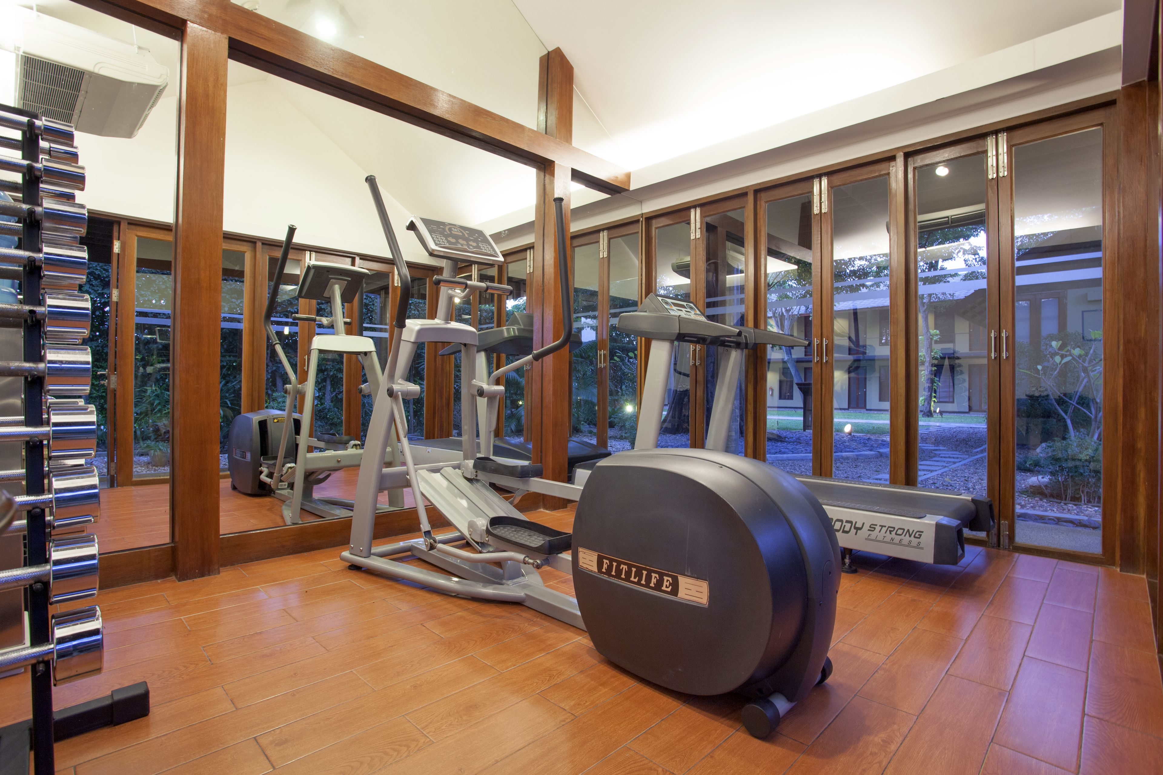 Un gimnasio con máquinas de cardio, una banca de pesas y una cinta de correr.