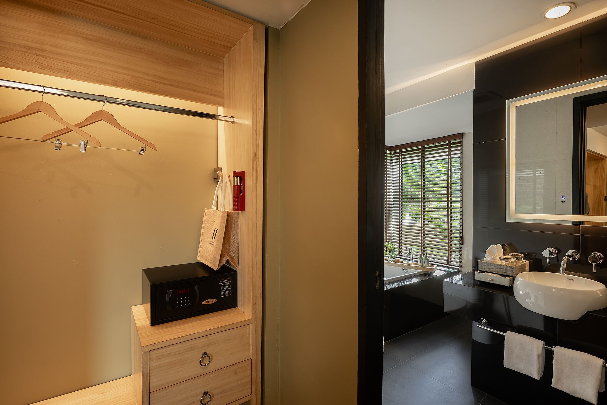 Ein modernes Badezimmer mit einem Holzwaschtisch, einer schwarzen Mikrowelle und einem großen Spiegel über dem Waschbecken.
