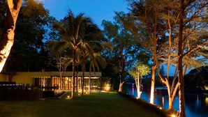 A modern house with a pool, surrounded by trees and illuminated by warm lights. - U Inchantree Kanchanaburi (Kanchanaburi)