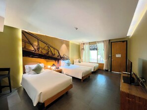 A hotel room with two beds, a wooden headboard, a nightstand with a lamp, and a large window with curtains. - U Inchantree Kanchanaburi (Kanchanaburi)