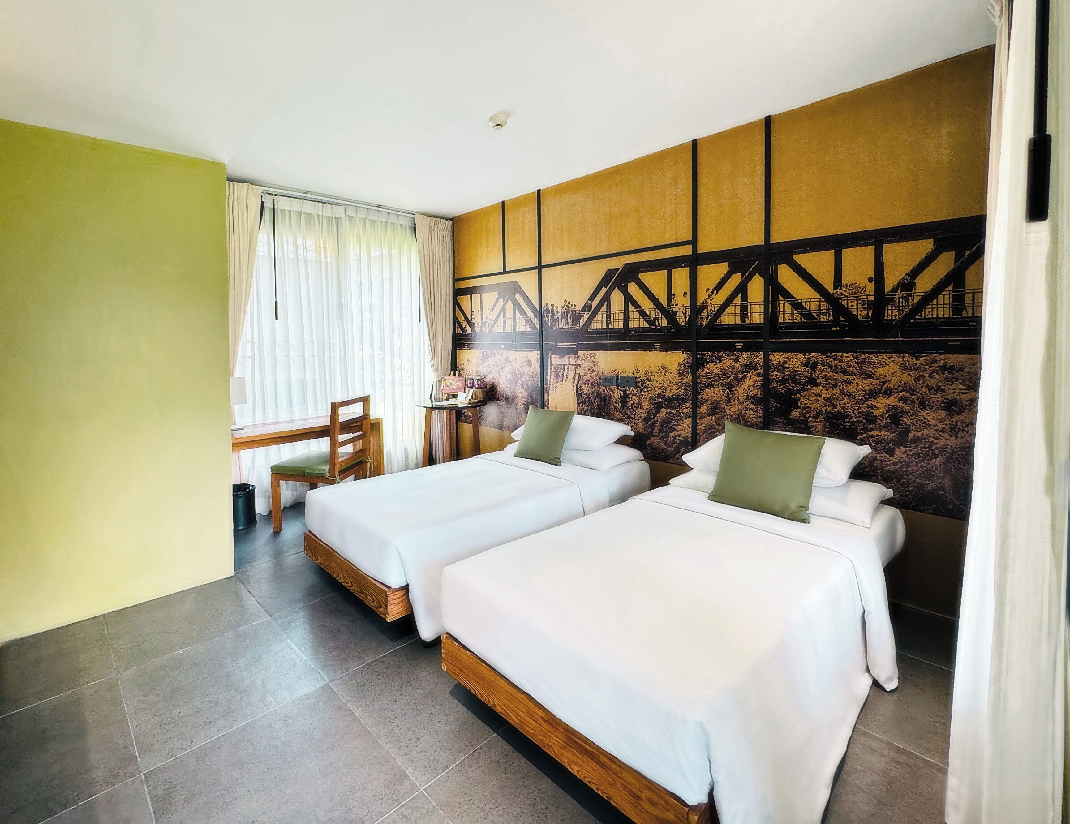 A hotel room with two beds, a small table, and a chair.