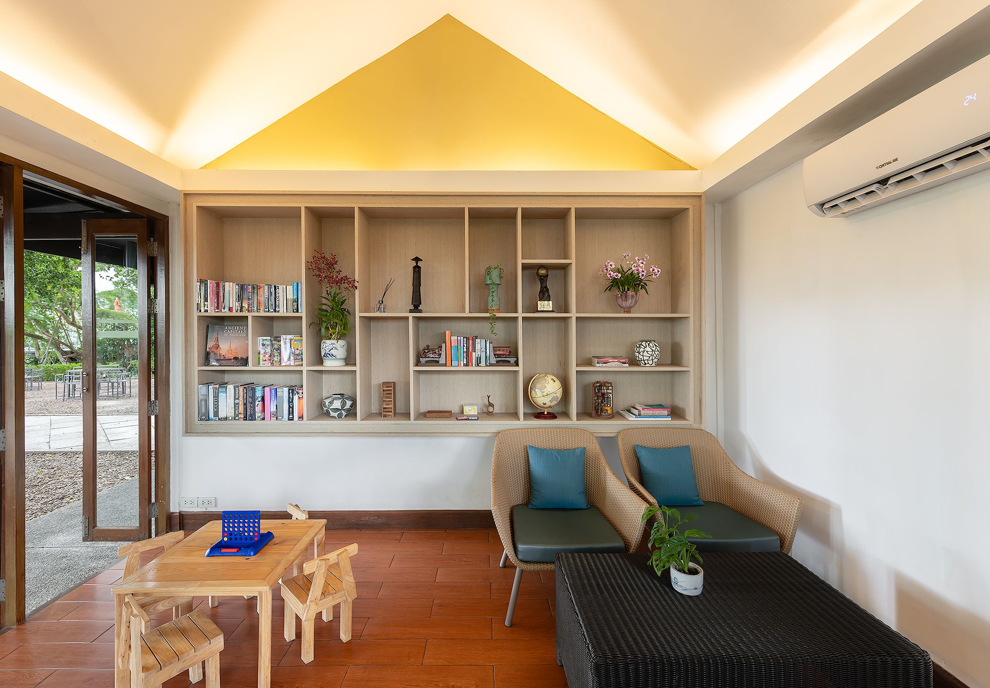 Ein modernes Wohnzimmer mit integriertem Bücherregal, einer Couch, einem Couchtisch und einem Essbereich mit Stühlen.