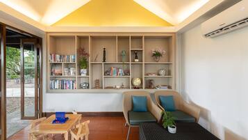 Ein modernes Wohnzimmer mit integriertem Bücherregal, einer Couch, einem Couchtisch und einem Essbereich mit Stühlen.