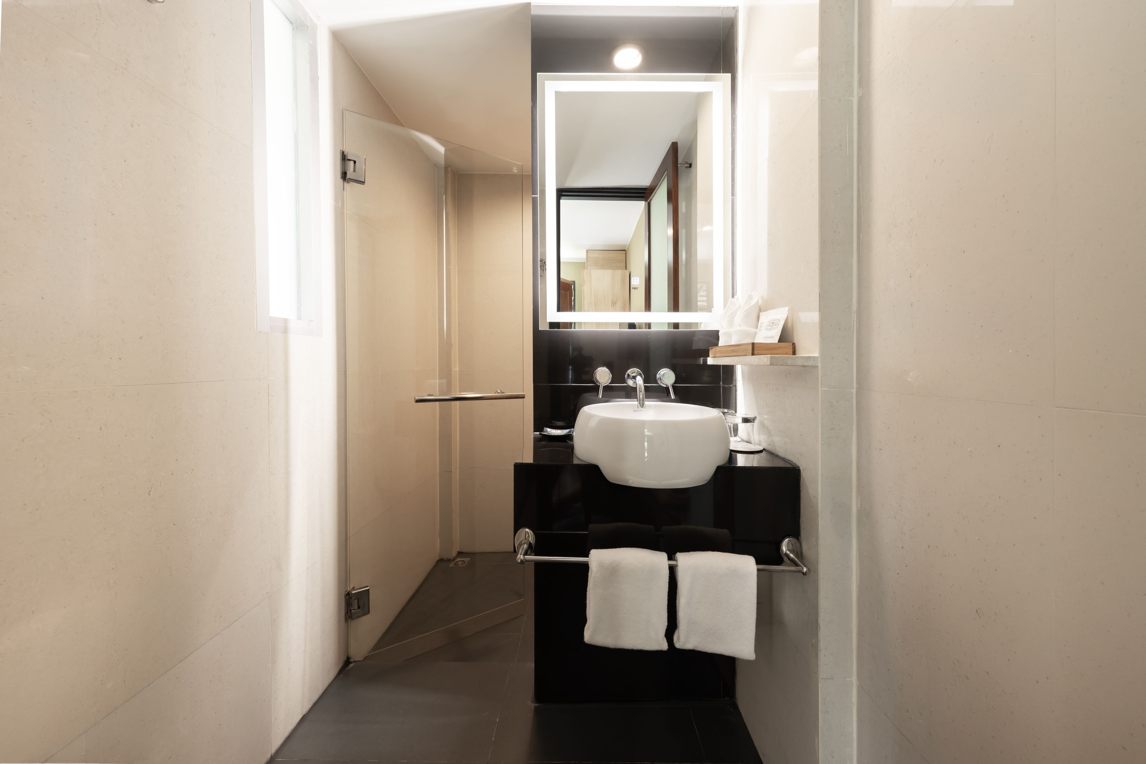 A modern bathroom with a white sink, black countertop, and a mirror above the sink.