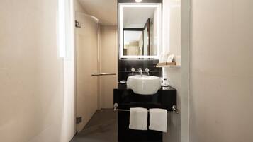 A modern bathroom with a white sink, black countertop, and a mirror above the sink.