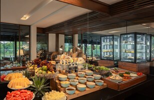 A buffet with various food items and a view of the outdoors through large windows.