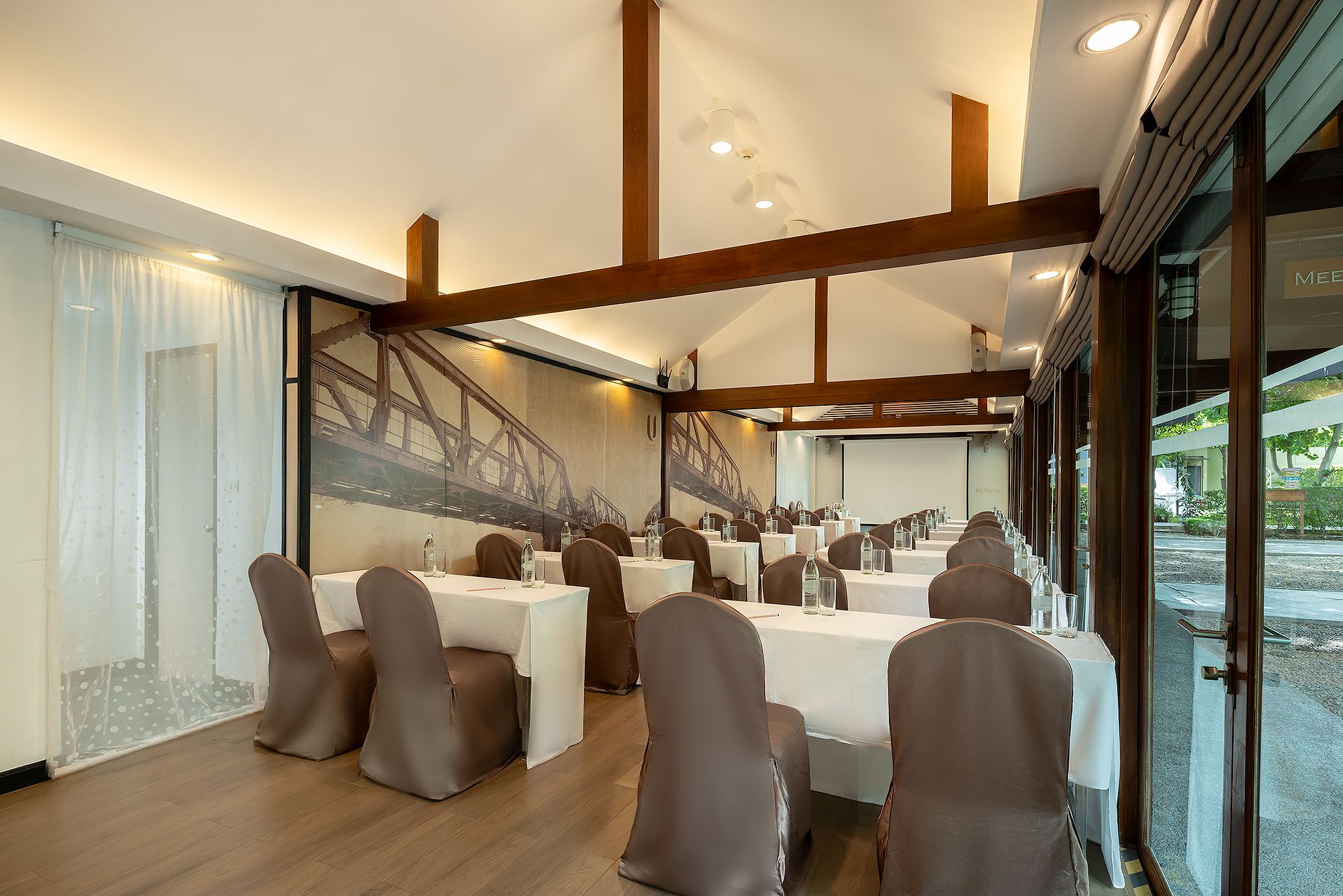 A conference room with tables and chairs, large windows, and a view of a bridge outside.