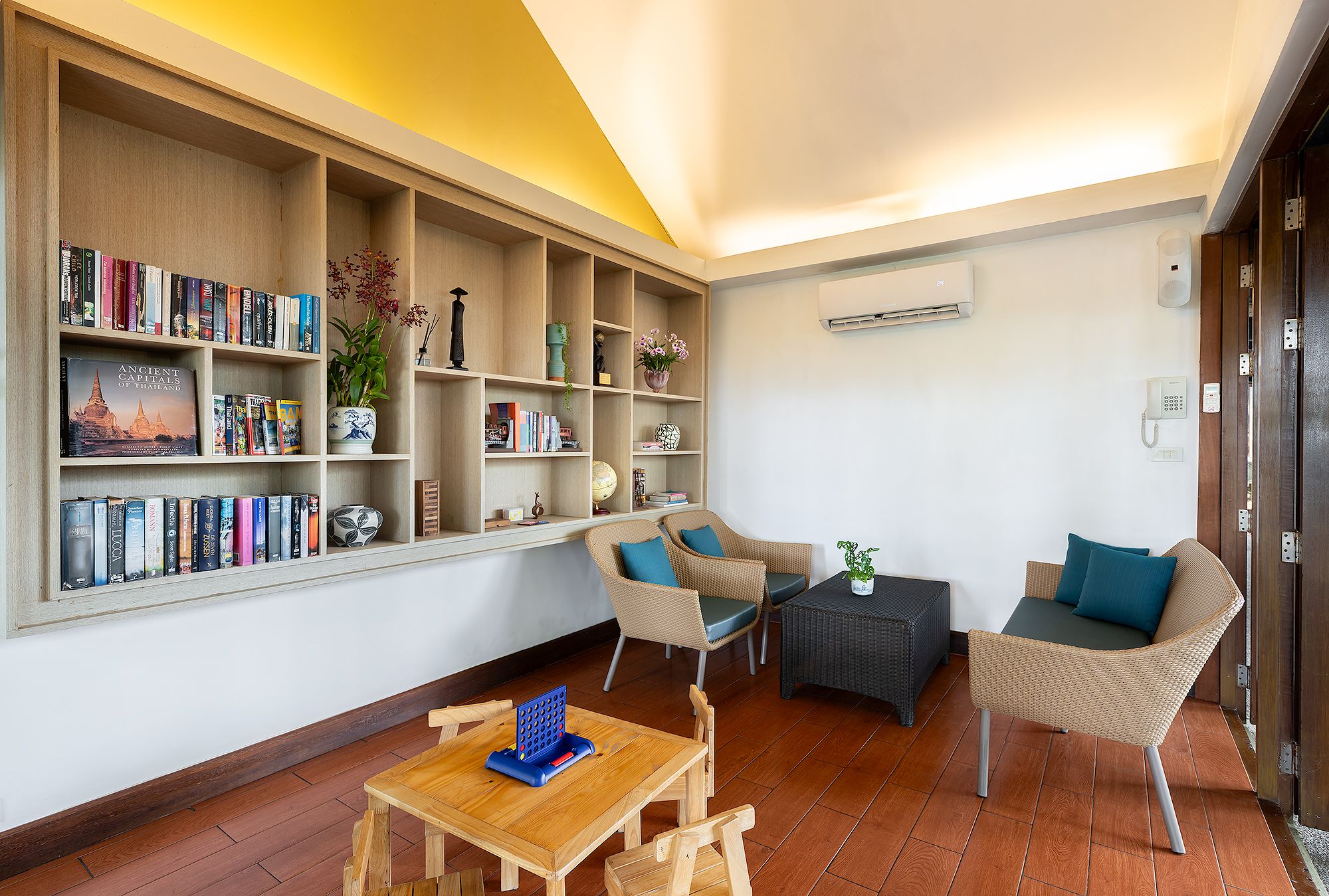 A cozy living room with a bookshelf, wicker furniture, and a small table.