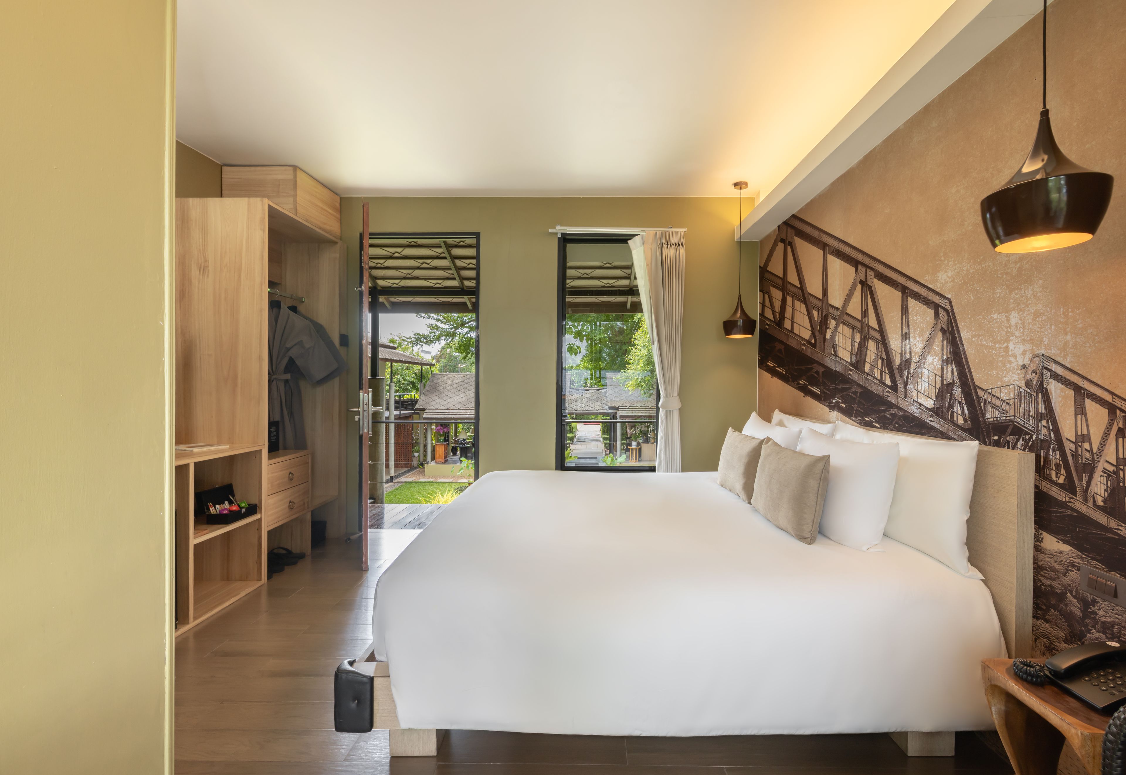 A bedroom with a large bed, wooden wardrobe, and a view of a garden.