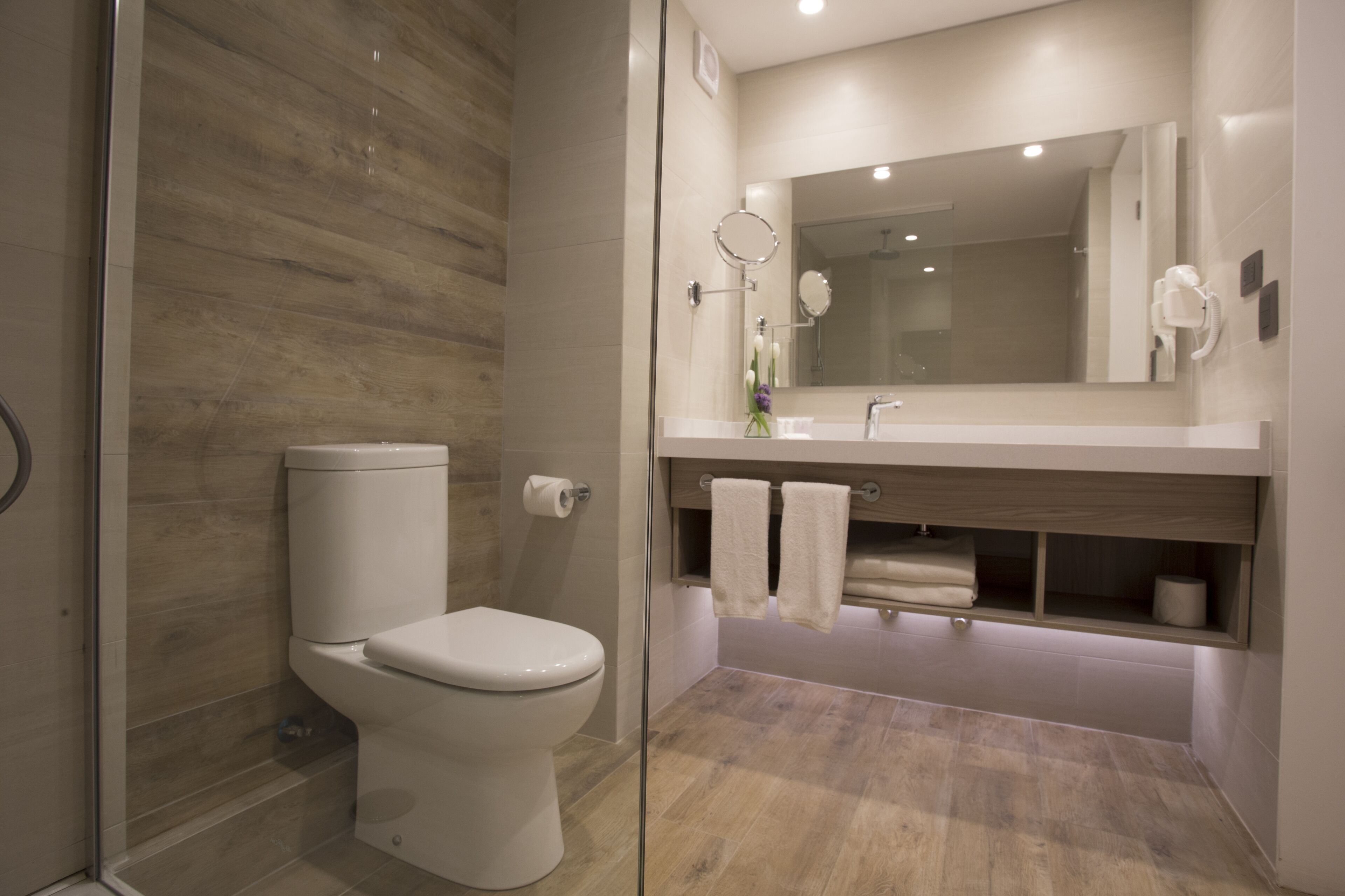 Une salle de bain moderne comprenant des toilettes, un lavabo avec un miroir et un espace douche.