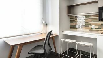A modern kitchen with a wooden countertop, a black office chair, and two white bar stools.