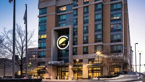 A hotel with a prominent circular logo, multiple floors, and a parking area. - Element by Marriott Omaha Midtown Crossing (Omaha)
