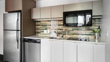 A modern kitchen with stainless steel appliances, a tiled backsplash, and white cabinetry.