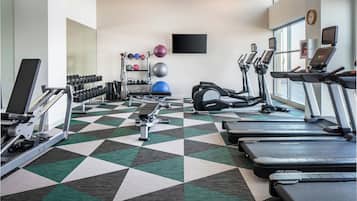 Un gimnasio con cintas de correr, elípticas y pesas libres.