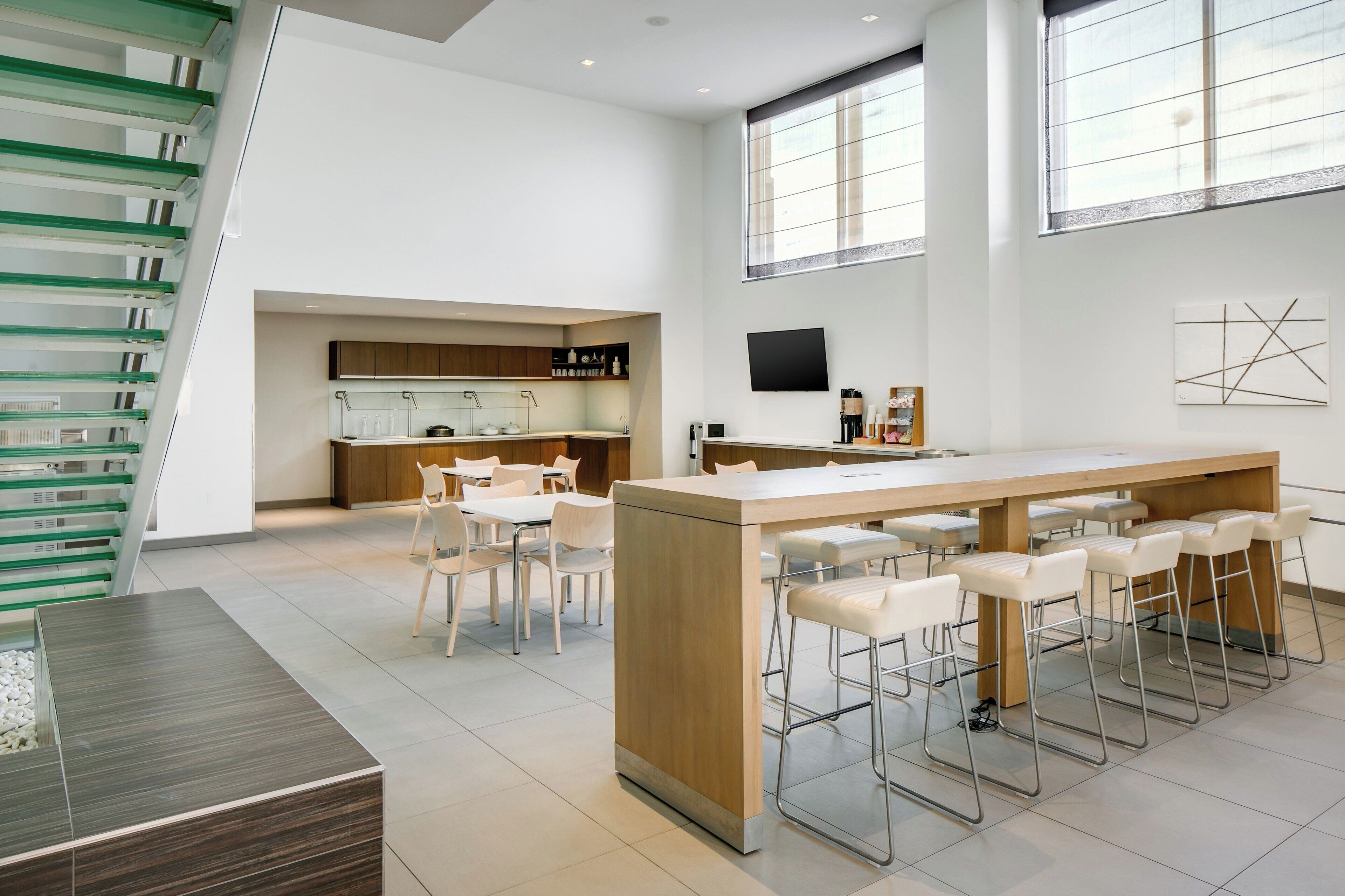 A modern kitchen with a central island, bar stools, and a dining area with chairs.