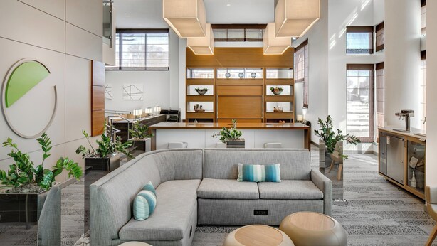 A modern interior with a sectional sofa, a kitchen area, and a dining space. - Element by Marriott Omaha Midtown Crossing (Omaha)