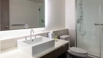 A modern bathroom with a large white sink, a toilet, and a glass-enclosed shower.
