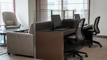 A modern office space with a desk, two chairs, and a sofa.