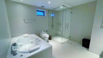 A modern bathroom with a large bathtub, a glass-enclosed shower, and a toilet.