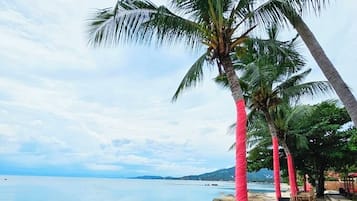 Na praia, areia branca, barracas de praia de cortesia, espreguiçadeiras