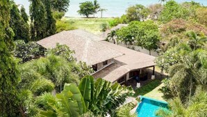 A house with a thatched roof, surrounded by lush greenery and a swimming pool. - Beach Republic, Koh Samui (Koh Samui)