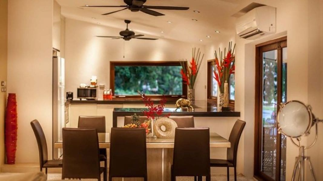 Un comedor moderno con un televisor de pantalla plana grande, un ventilador de techo y una mesa de comedor con sillas.