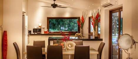 Un comedor moderno con un televisor de pantalla plana grande, un ventilador de techo y una mesa de comedor con sillas.