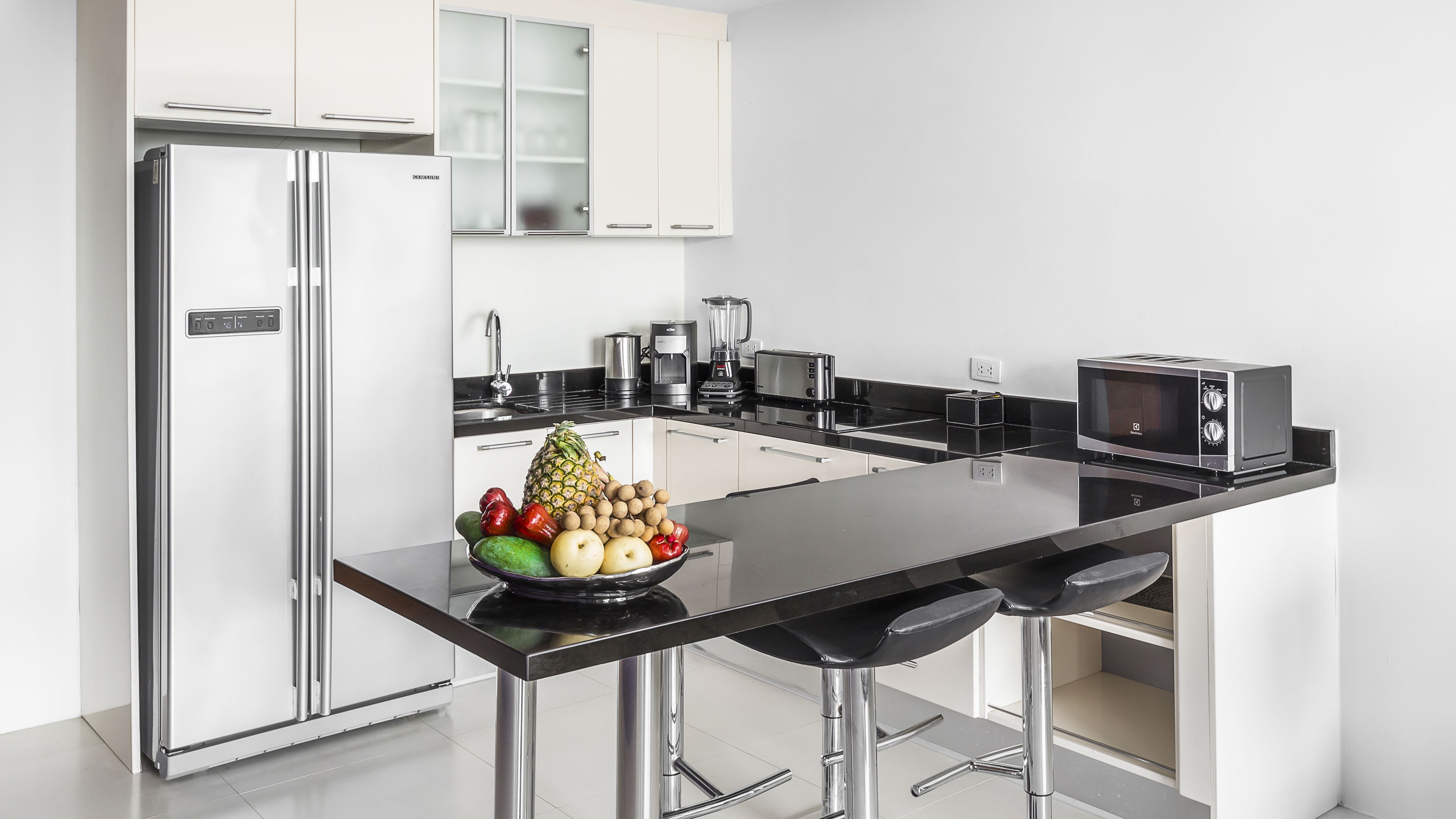 Een moderne keuken met roestvrijstalen apparatuur, een centraal kookeiland met een fruitschaal, en een magnetron.