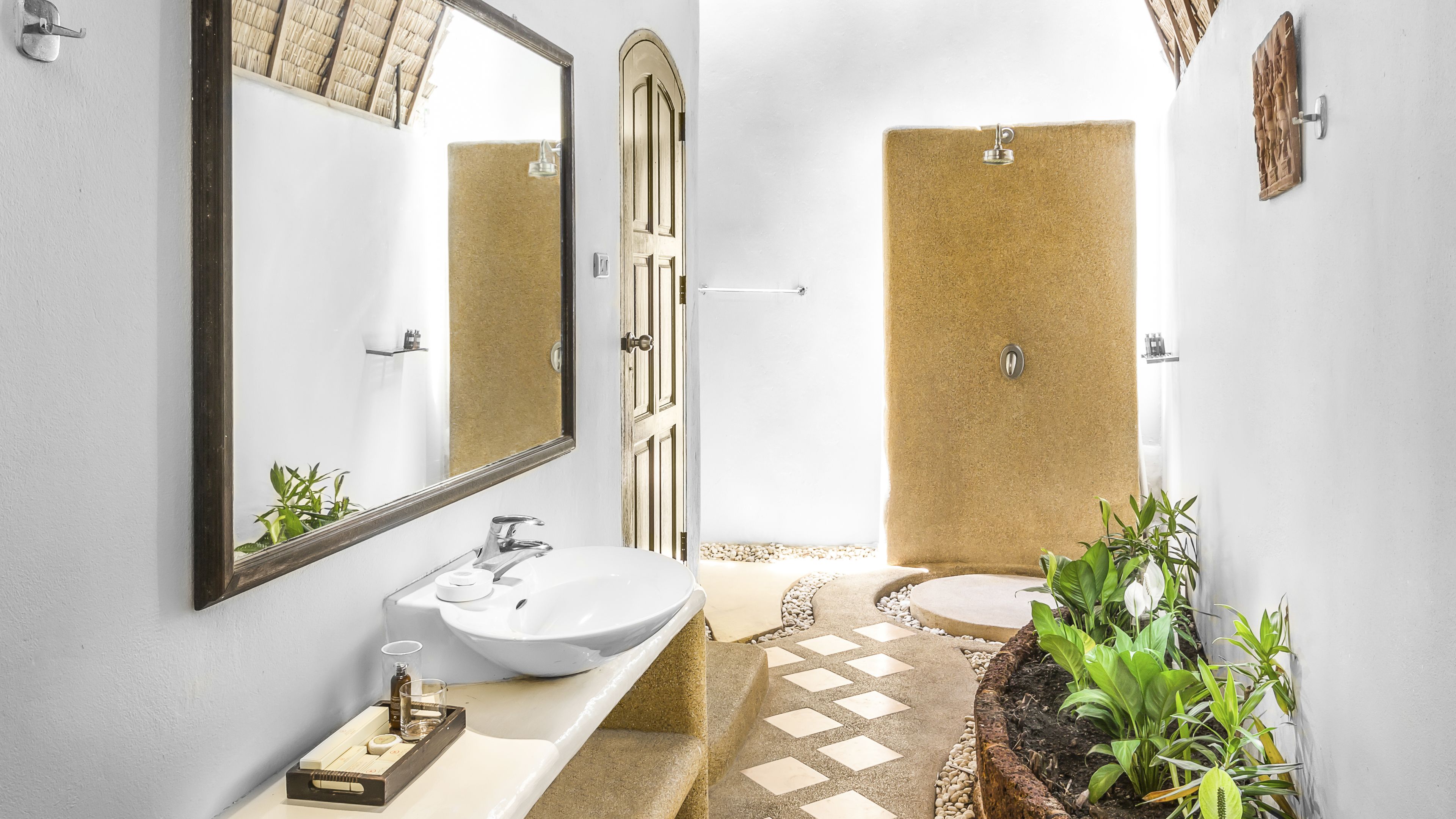Un baño con un espejo grande, un lavamanos, una ducha y un inodoro pequeño.