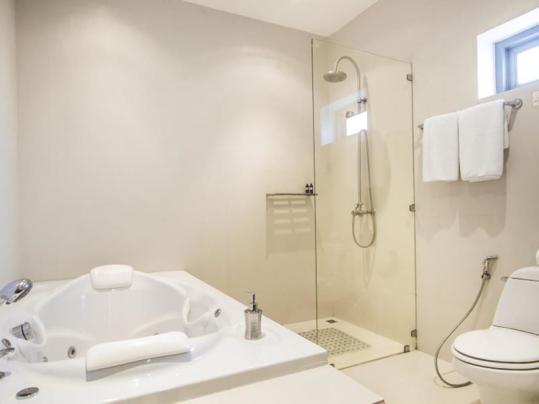 Ein modernes Badezimmer mit einer gläsernen Duschkabine, einer freistehenden Badewanne und einer Toilette.