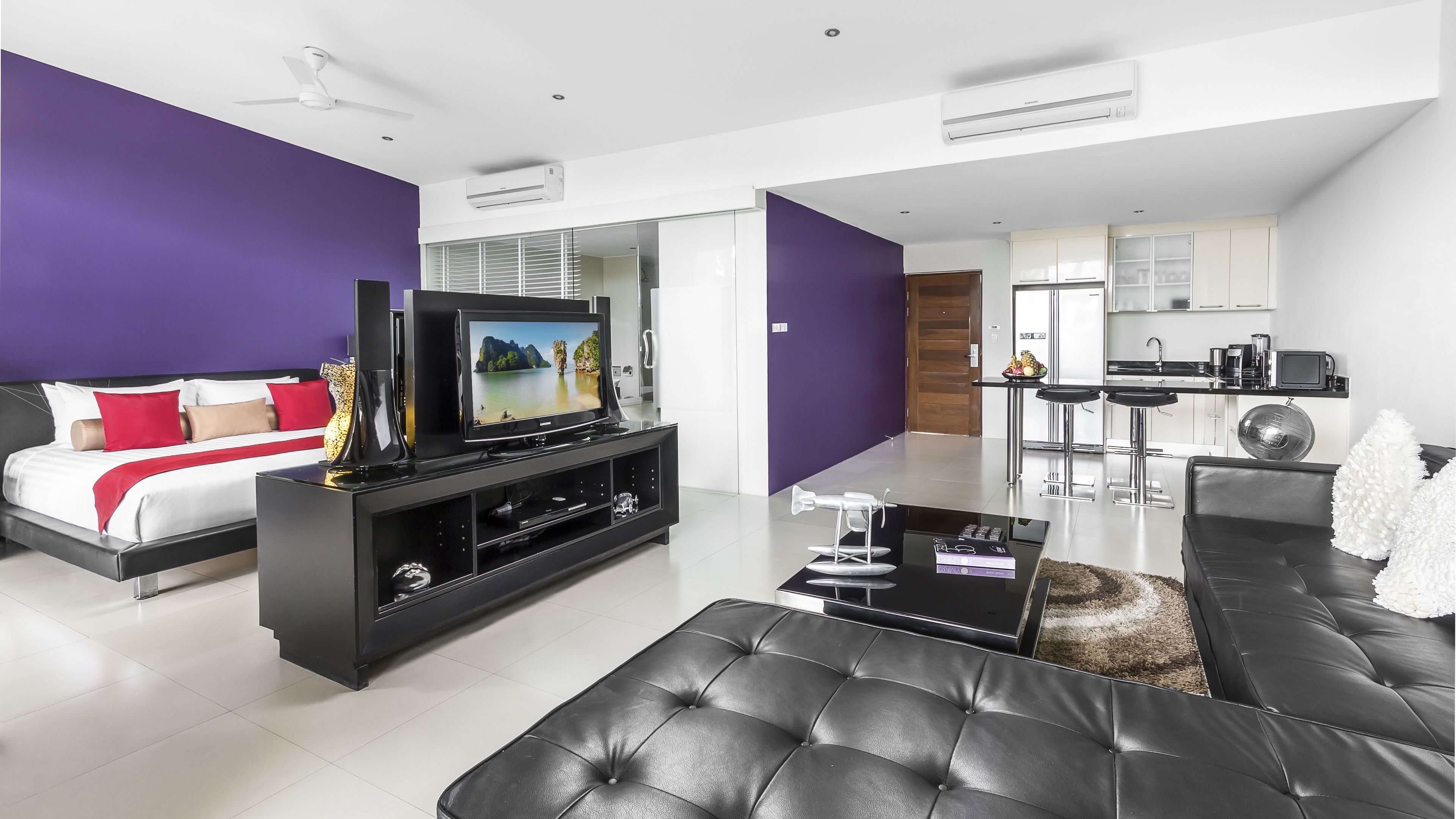 Una sala de estar moderna con un televisor de pantalla plana, un sofá negro y un comedor con barra.