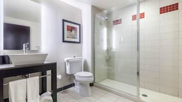 Un baño moderno con ducha de vidrio, inodoro, lavabo con espejo y toallero con toallas.