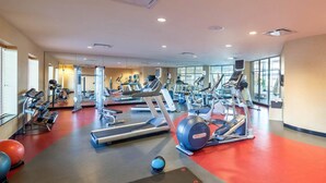 Un gimnasio con cintas de correr, elípticas y pesas libres.