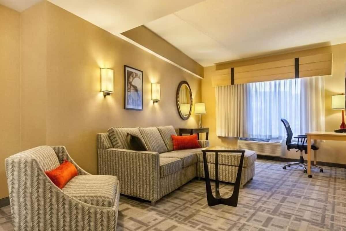 A hotel room with a sofa, armchair, and a small table.