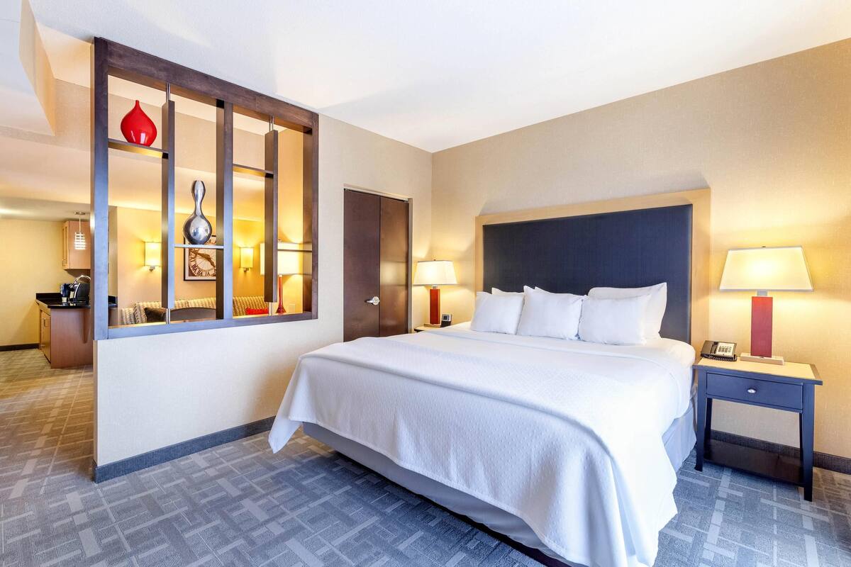 A hotel room with a large bed, two bedside tables, a nightstand, a desk, and a chair.