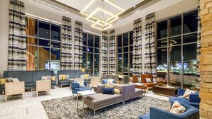 Amplia sala de estar con un sofá moderno, sillones y una mesa de centro. Grandes ventanales ofrecen vista a la ciudad de noche.