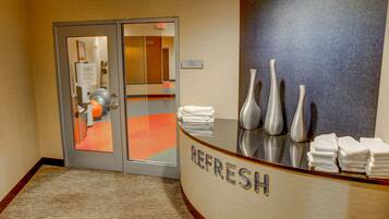 A reception area with a glass door, a counter with towels, and three vases.