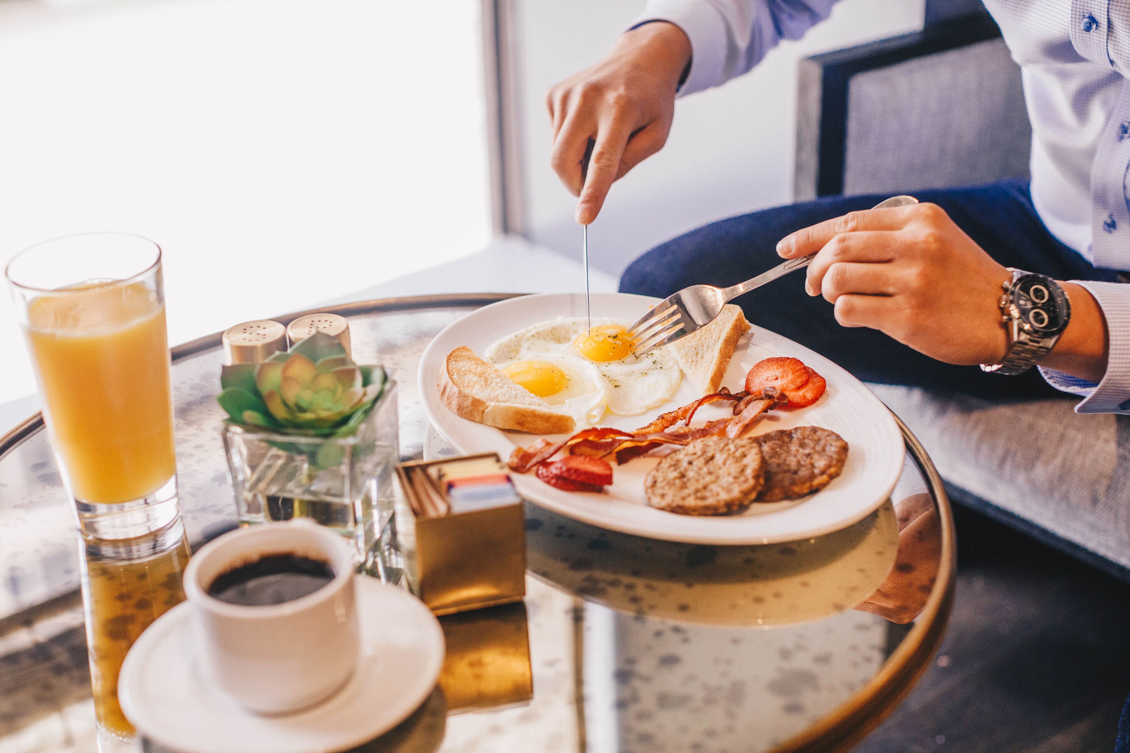 A breakfast tray with eggs, bacon, toast, and a glass of orange juice.