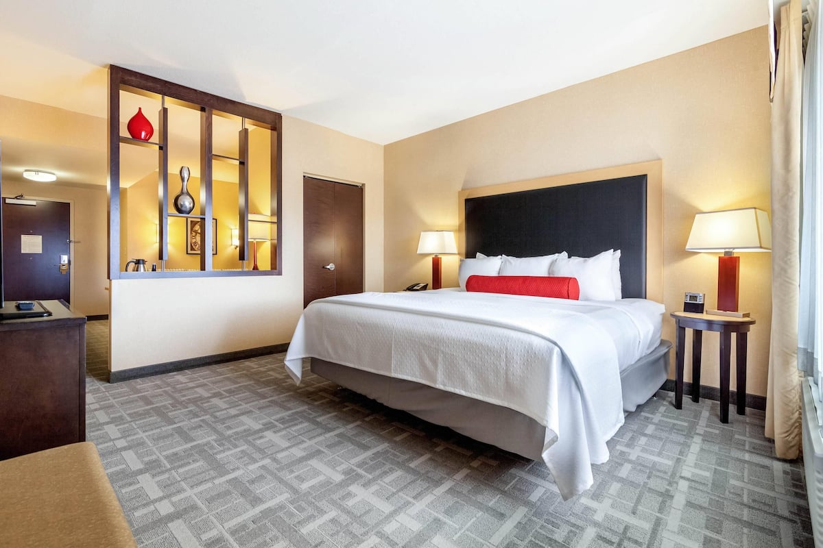 A hotel room with a large bed, bedside lamps, a desk, and a mirror.