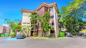 A building with a sign reading "HANA KAWA" and a parking lot with two cars. - Hono Koa Vacation Club (Lahaina)