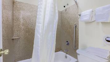 A bathroom with a bathtub, toilet, and shower curtain.