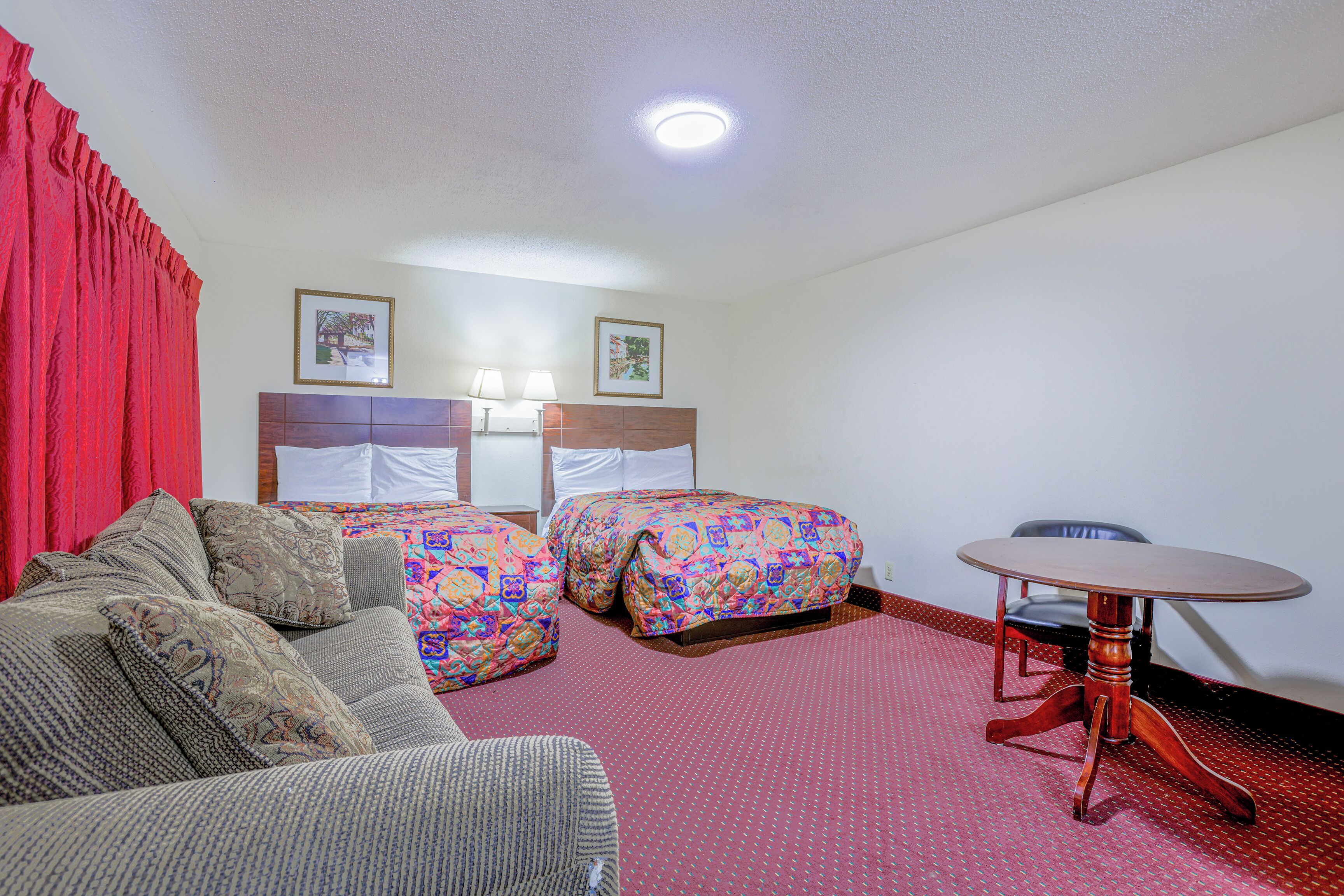 Una camera d'albergo con un letto, un divano, un tavolo e due sedie.