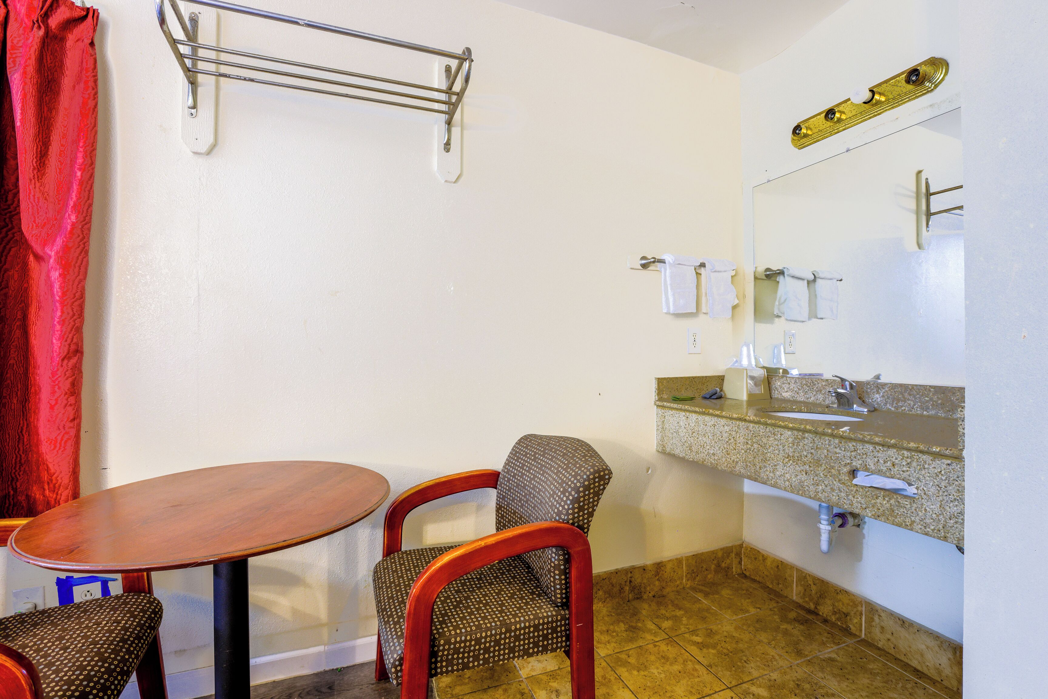 A bathroom with a sink, mirror, towel rack, and a table with chairs.