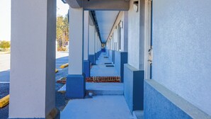 A corridor with a series of rooms, each with a door and a window. - Whispering Pines by Hotel O Whitestone VA (White Stone)