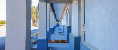 Un pasillo con varias habitaciones, cada una con una puerta y una ventana.