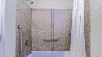 Une salle de bain équipée d’une baignoire, de barres d’appui et d’un rideau de douche.