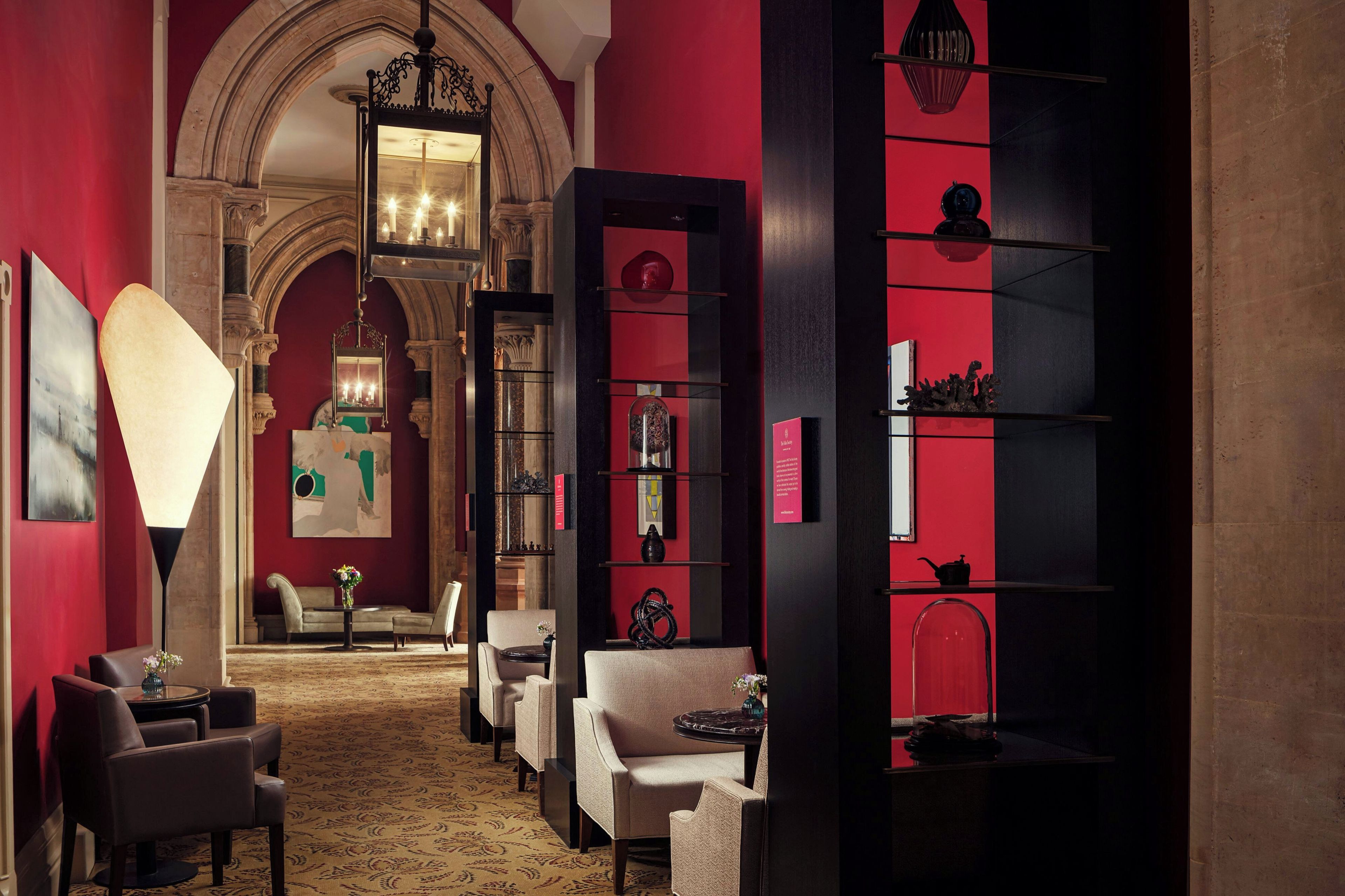 A hotel lobby with a grand archway, a chandelier, and a red and black color scheme.
