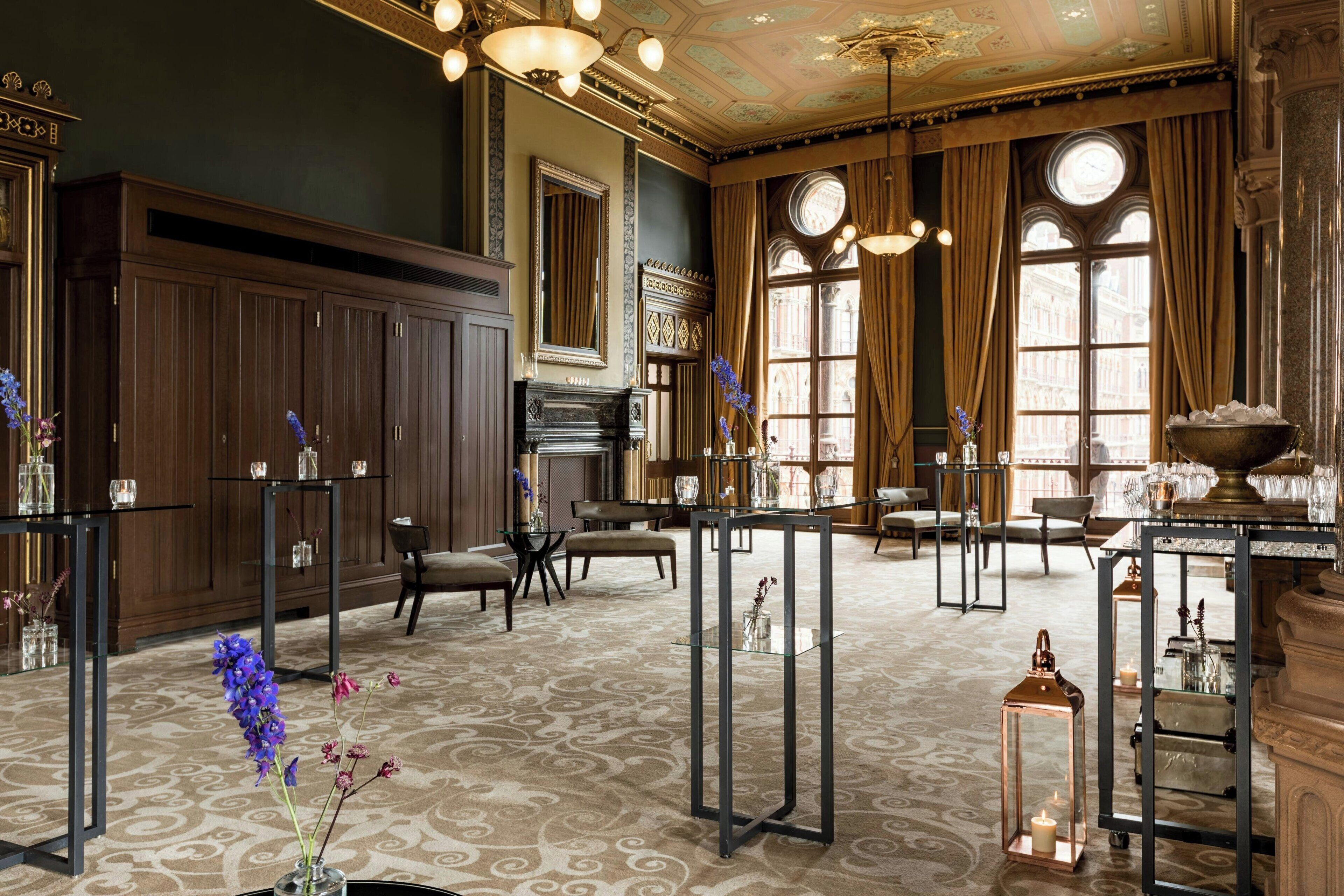 A spacious room with a patterned carpet, wooden furniture, and large windows with curtains.