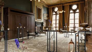 A spacious room with a patterned carpet, wooden furniture, and large windows with curtains.