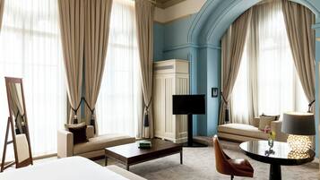 Une chambre d’hôtel avec un lit, un canapé, une table basse, une télévision et une lampe.